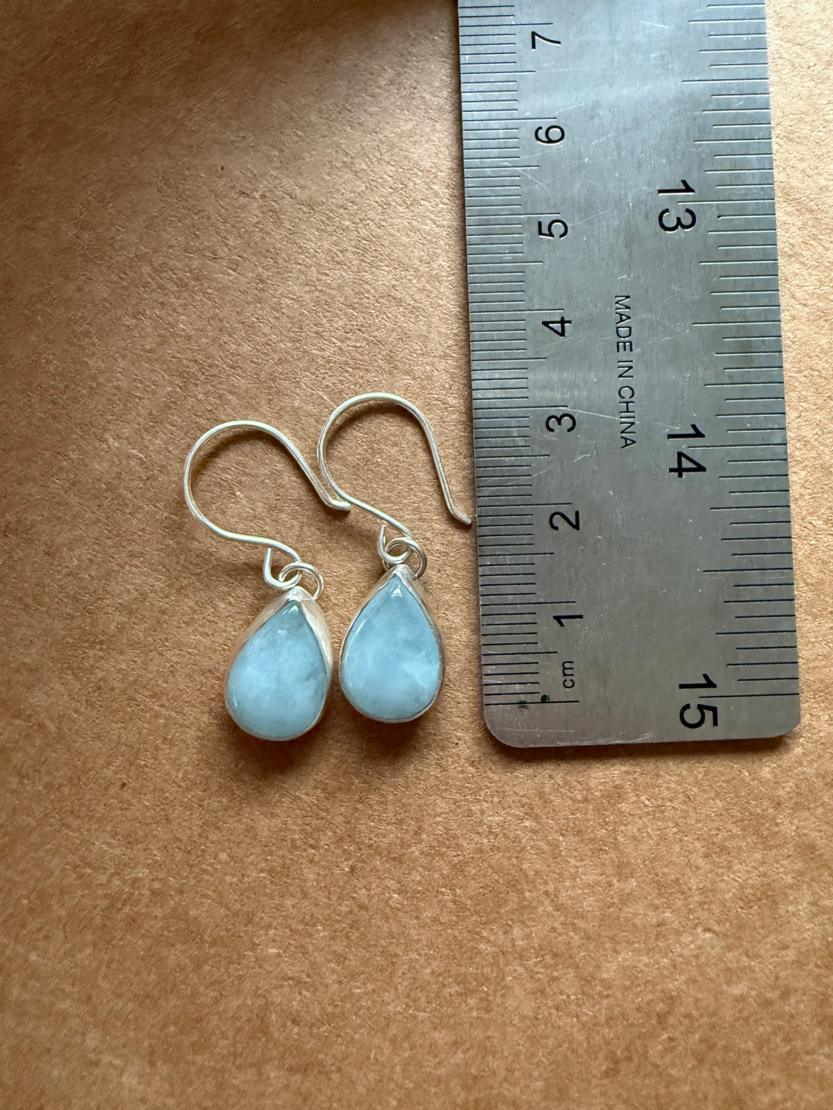 aquamarine tear shaped drop earrings next to ruler in centimeters